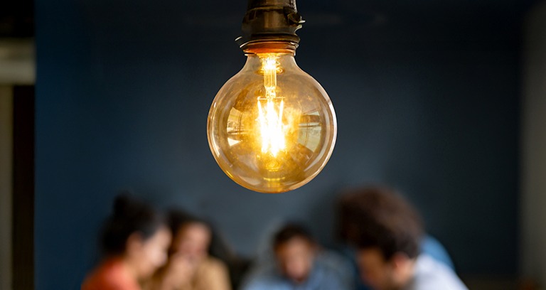 people around table with a light bulb in focus