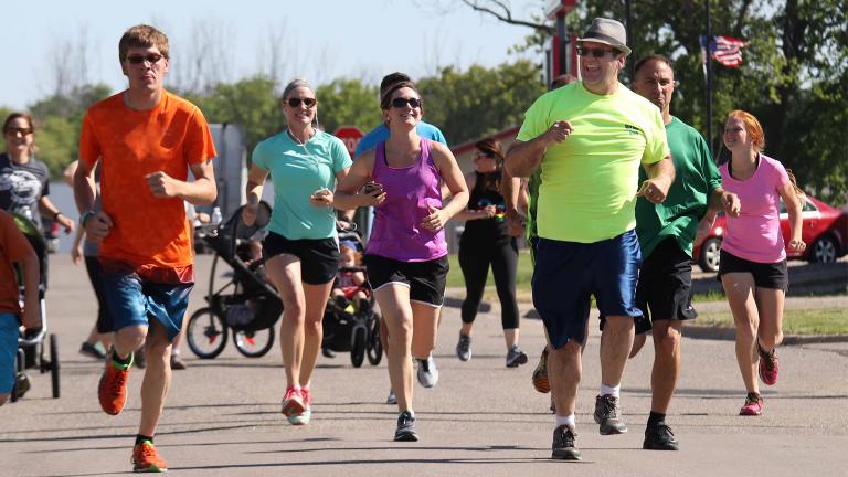 a happy group of adults and teens competing in a 5k fun run