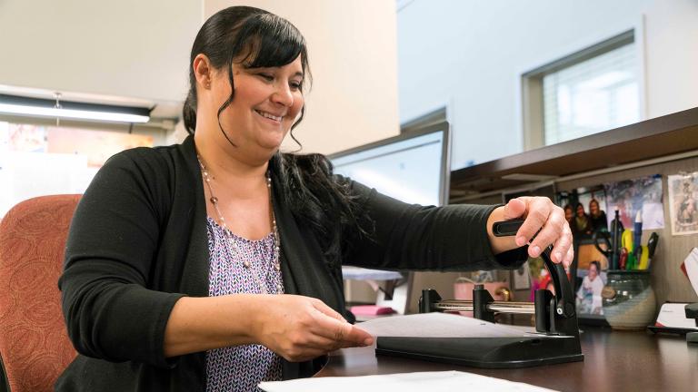 a smiling Sourcewell staff member working at her desk